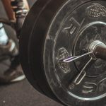 Close-up of a weightlifter's legs and barbell during a workout session.